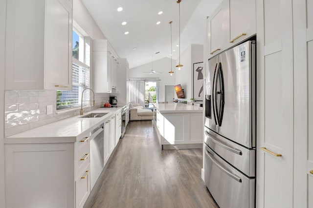 kitchen featuring stainless steel appliances, vaulted ceiling, sink, and white cabinetry