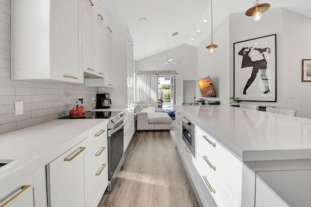 kitchen featuring pendant lighting, appliances with stainless steel finishes, white cabinetry, decorative backsplash, and vaulted ceiling