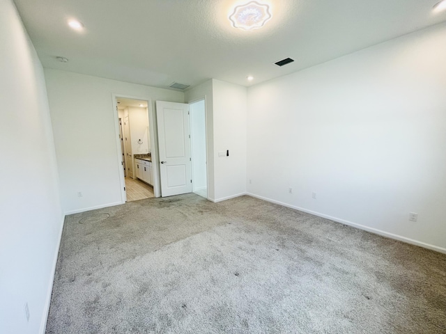 unfurnished bedroom featuring connected bathroom and light colored carpet