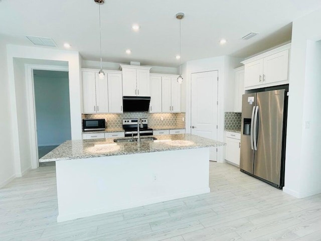 kitchen featuring light stone countertops, an island with sink, white cabinets, stainless steel appliances, and a sink