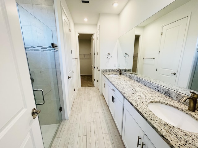 bathroom with hardwood / wood-style flooring, vanity, and a shower with shower door