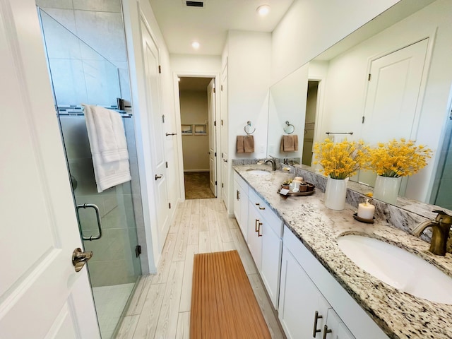 full bath featuring a sink, a shower stall, wood finished floors, and a spacious closet