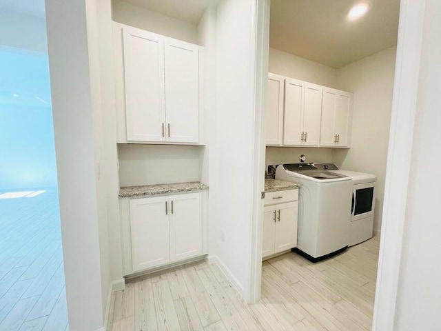 laundry area with washer / clothes dryer, cabinets, and light hardwood / wood-style floors