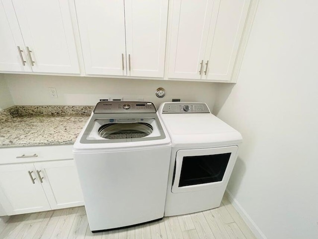 laundry room with cabinets, washing machine and dryer, and light hardwood / wood-style flooring