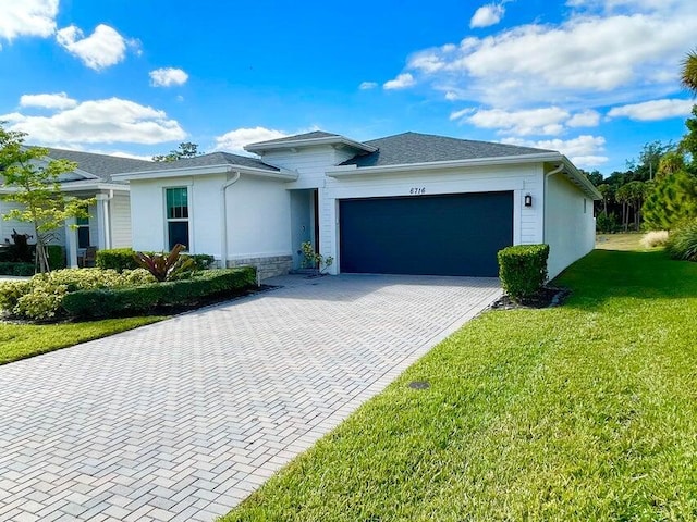 view of front of property with stucco siding, a front yard, decorative driveway, and a garage