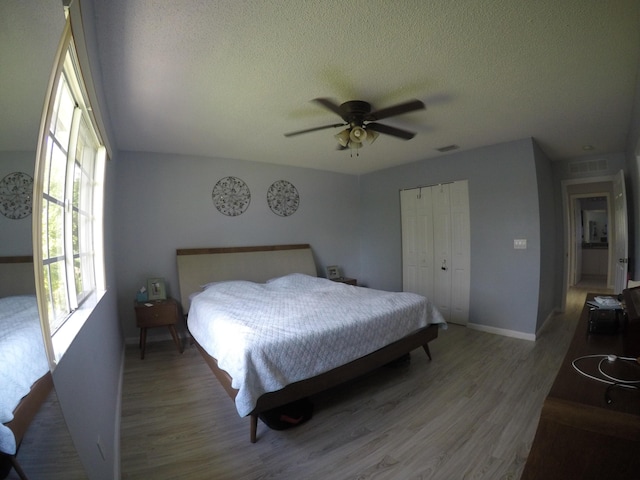 bedroom featuring a textured ceiling, a closet, wood finished floors, and visible vents