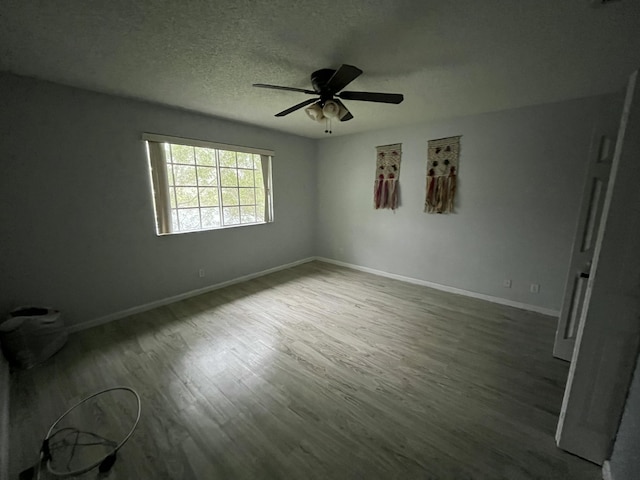 interior space with a ceiling fan, a textured ceiling, baseboards, and wood finished floors