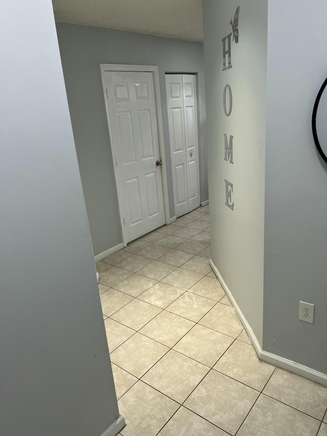 hall featuring light tile patterned floors and baseboards