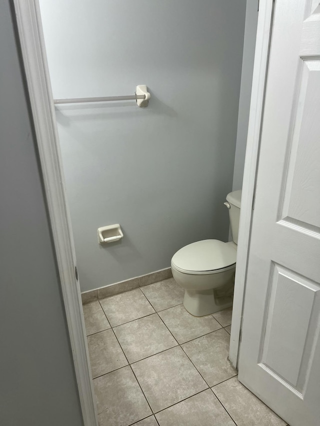 bathroom with toilet, baseboards, and tile patterned floors