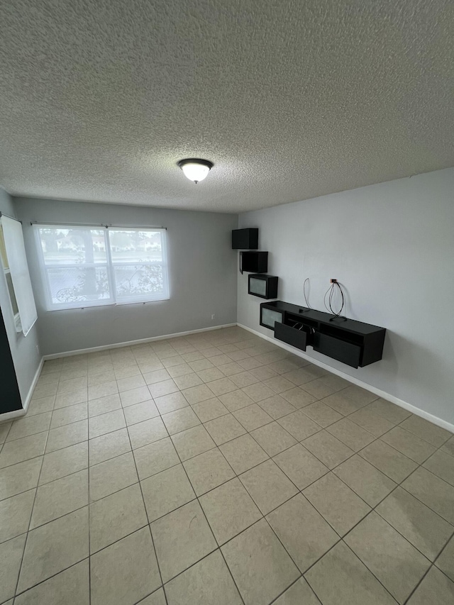 interior space featuring light tile patterned floors, a textured ceiling, and baseboards