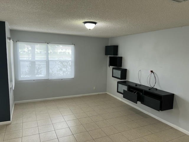 unfurnished living room with a textured ceiling, light tile patterned floors, and baseboards