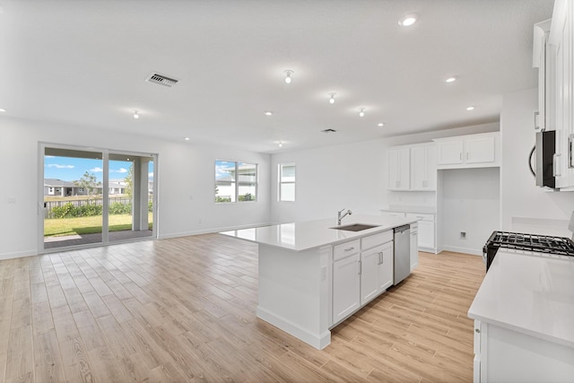 kitchen featuring sink, white cabinetry, a center island with sink, light wood-type flooring, and appliances with stainless steel finishes