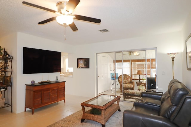 tiled living room with ceiling fan and a textured ceiling