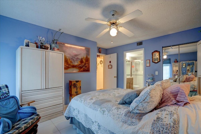 tiled bedroom with ensuite bathroom, a textured ceiling, and ceiling fan