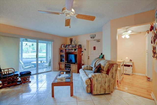 living room featuring ceiling fan, a textured ceiling, and light tile patterned floors