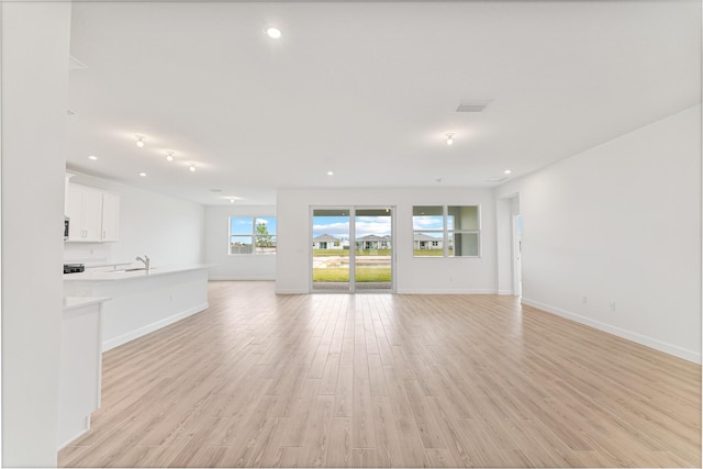 unfurnished living room with sink and light wood-type flooring