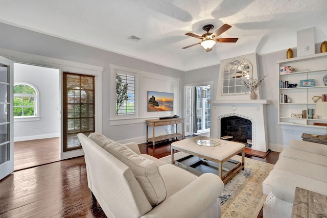 living room featuring a textured ceiling, dark wood-type flooring, and ceiling fan