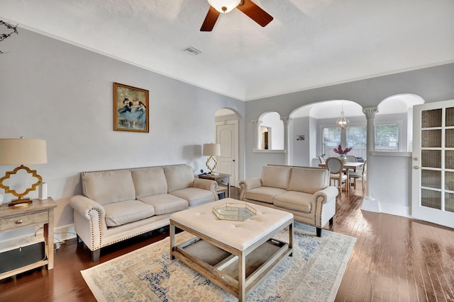 living room with dark wood-type flooring, ceiling fan, ornamental molding, and ornate columns