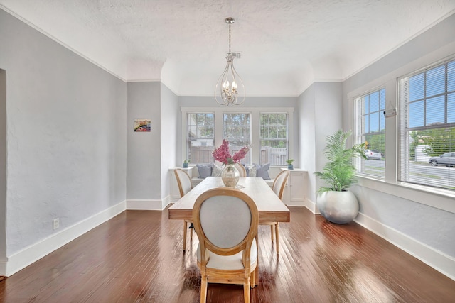 dining space featuring dark wood-type flooring, a wealth of natural light, a textured ceiling, and a notable chandelier