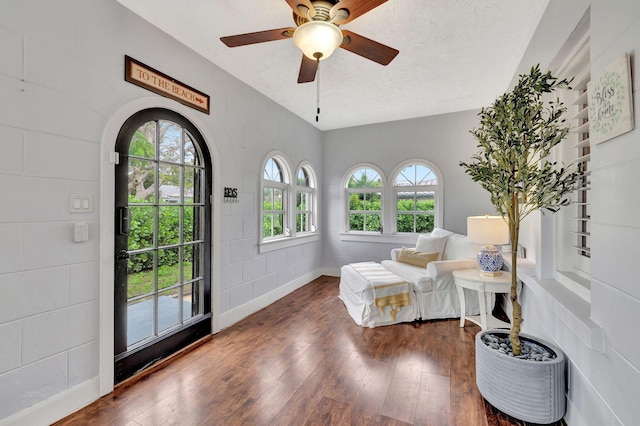 sitting room featuring ceiling fan, dark wood-type flooring, and a textured ceiling