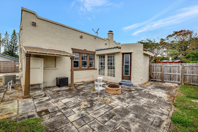 rear view of property featuring cooling unit, an outdoor fire pit, and a patio