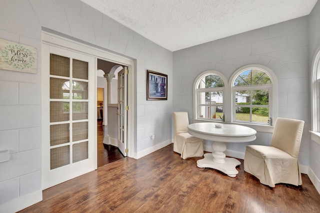 dining area with decorative columns, a textured ceiling, dark hardwood / wood-style flooring, and french doors