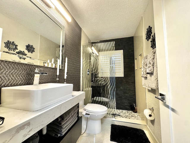 bathroom with tile patterned flooring, vanity, walk in shower, toilet, and a textured ceiling