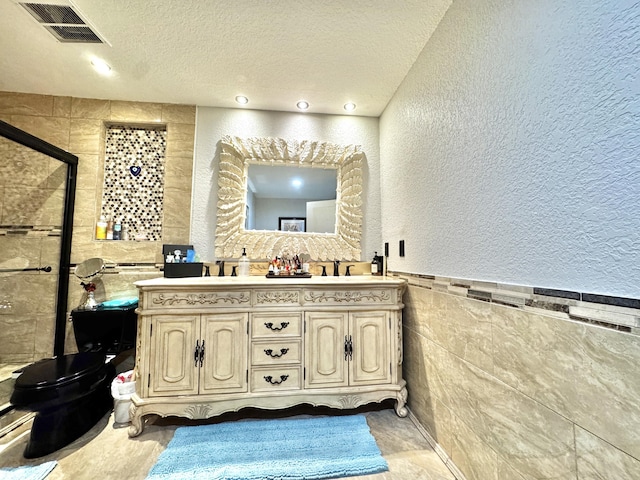 bathroom featuring vanity, a shower with door, tile walls, and a textured ceiling