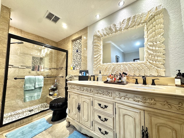 bathroom featuring an enclosed shower, vanity, a textured ceiling, and toilet