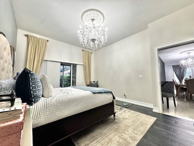 bedroom with dark wood-type flooring, a textured ceiling, and an inviting chandelier