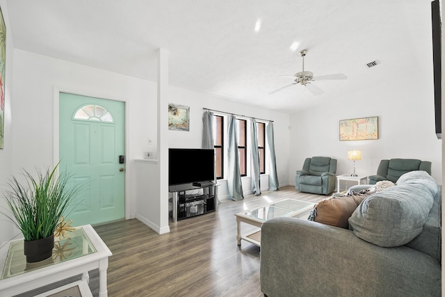 living room with wood finished floors, visible vents, baseboards, vaulted ceiling, and a ceiling fan