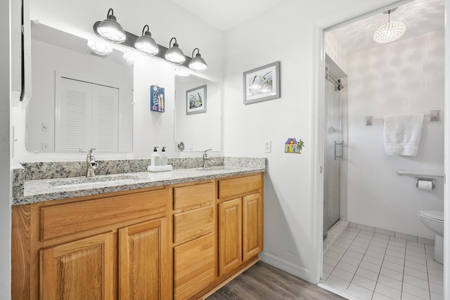 bathroom featuring a stall shower, a sink, toilet, and double vanity