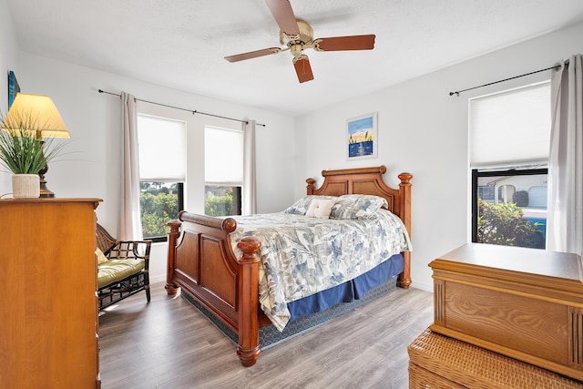 bedroom featuring ceiling fan, a textured ceiling, baseboards, and wood finished floors