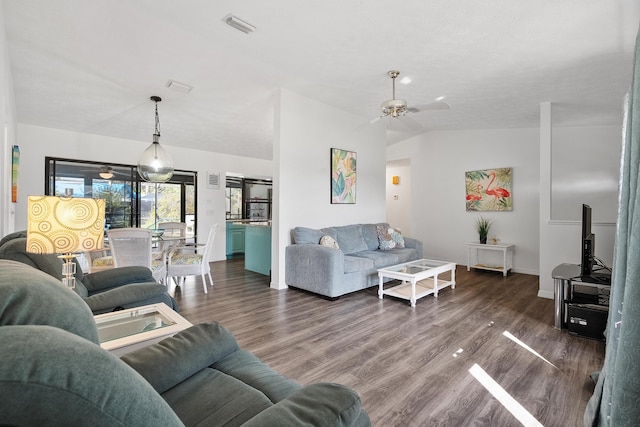 living area with dark wood-type flooring, visible vents, vaulted ceiling, and ceiling fan