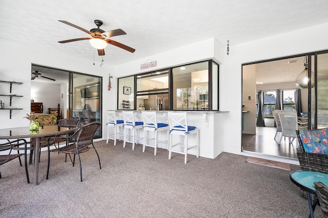 carpeted dining space featuring ceiling fan and a textured ceiling