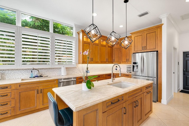 kitchen featuring a kitchen island with sink, sink, crown molding, and appliances with stainless steel finishes