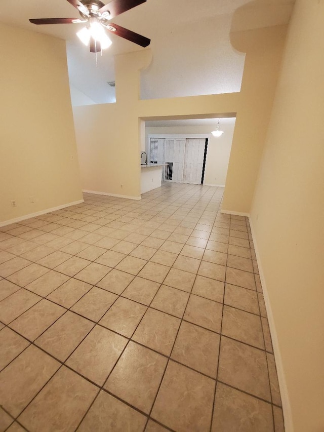 unfurnished room with light tile patterned flooring, a towering ceiling, and ceiling fan