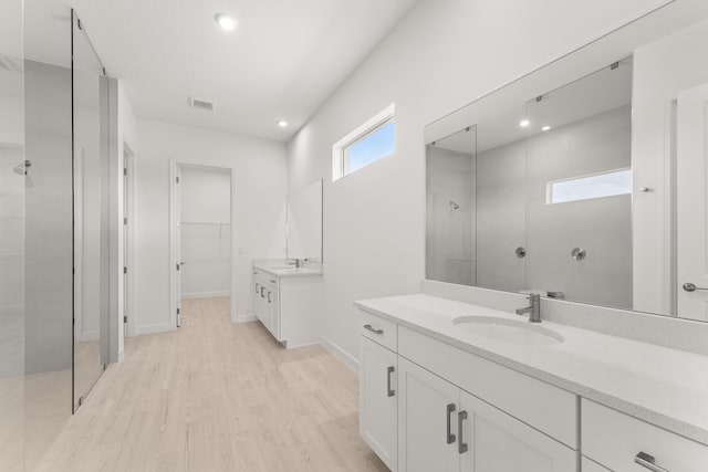 full bathroom with walk in shower, wood finished floors, visible vents, and a sink