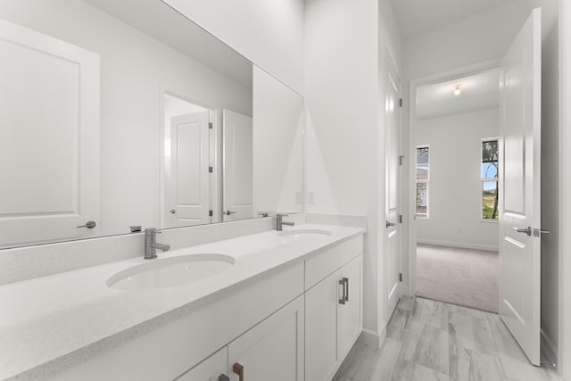 bathroom featuring double vanity, baseboards, and a sink