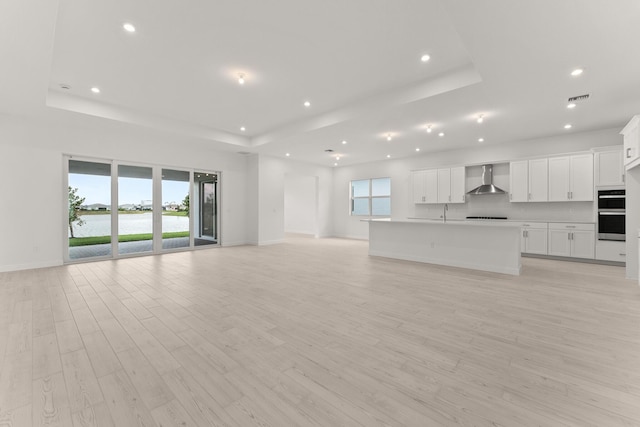 unfurnished living room with a wealth of natural light, visible vents, and a tray ceiling