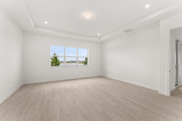 unfurnished room featuring recessed lighting, visible vents, a raised ceiling, and light wood-style floors