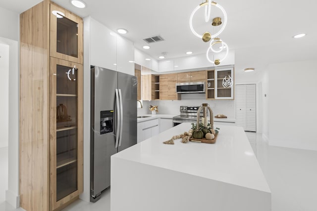 kitchen featuring a kitchen island, white cabinetry, appliances with stainless steel finishes, and pendant lighting