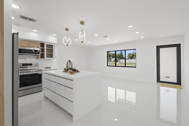 kitchen with appliances with stainless steel finishes, white cabinetry, hanging light fixtures, a center island, and light tile patterned floors