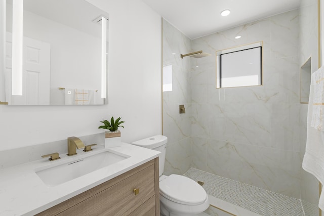 bathroom with vanity, toilet, and a tile shower