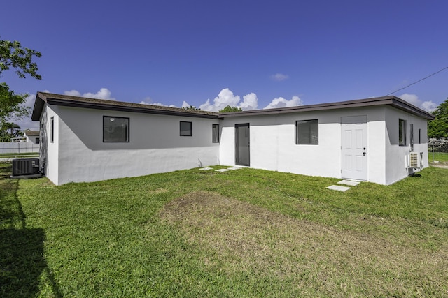 back of house with central AC and a lawn