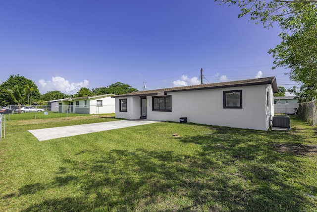 back of property with central AC unit, a patio area, and a lawn