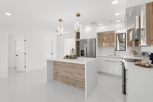 kitchen with stainless steel appliances, white cabinetry, sink, and decorative light fixtures