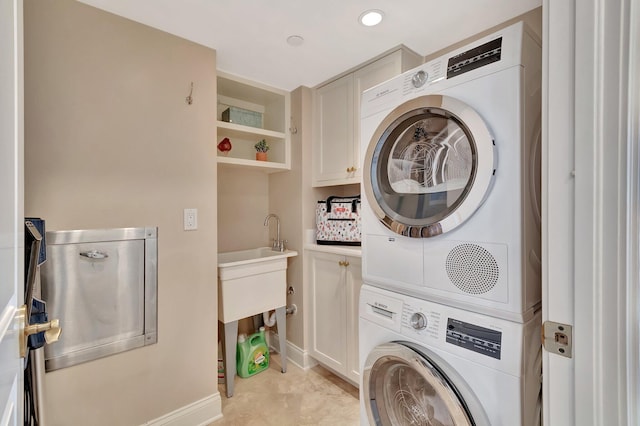 laundry room featuring cabinet space, baseboards, stacked washer / dryer, and recessed lighting