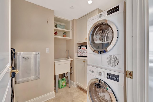 washroom featuring cabinet space, baseboards, stacked washer / dryer, and recessed lighting