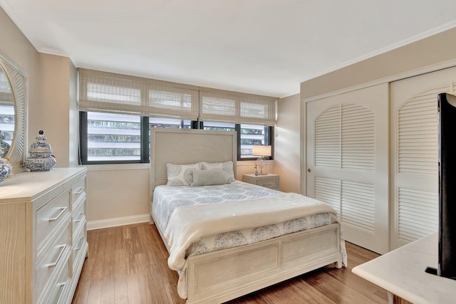 bedroom with a closet, light wood-style flooring, and baseboards